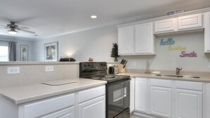 A modern kitchen with white cabinetry, a stainless steel stove, and a backsplash with decorative text. - Oceanview Condo OW 4203 in Oak Island: 2 bedrooms, sleeps 6, with stunning views! (Oak Island)