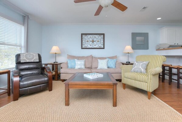 A living room with a leather armchair, a sofa, a striped armchair, and a coffee table.