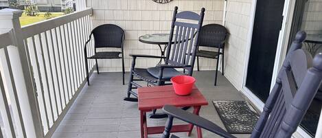 A balcony with two chairs, a small table, and a red bowl.