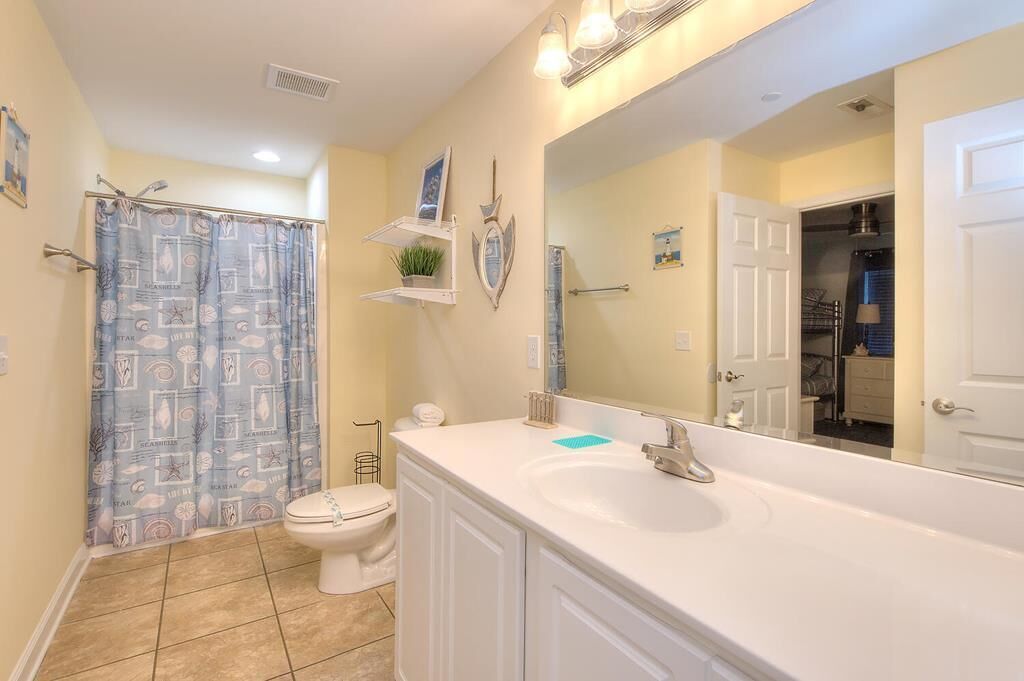 A bathroom with a white sink, a large mirror, and a shower curtain with a pattern.
