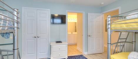A bedroom with bunk beds, a television, a white dresser, and a blue rug.