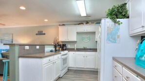 Une cuisine compacte avec des meubles blancs, une cuisinière encastrée et un réfrigérateur décoré d’une carte.