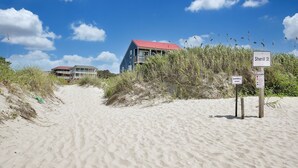 A beach with a sign for 'Sherill St' and a building with a red roof in the background.