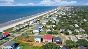 An aerial view of a coastal residential area with houses, a beach, and a clear sky.