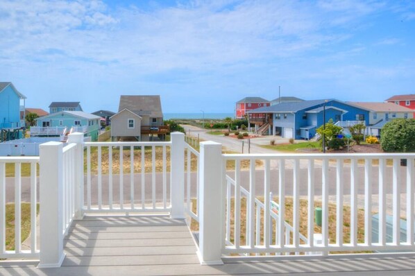 Un quartier résidentiel en bord de mer, avec des maisons, une terrasse en bois et un ciel dégagé.
