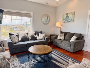 A living room with two grey sofas, a round coffee table, and a patterned rug. - Experience oceanfront luxury at Pirate's View in Oak Island—perfect for 16 guests! (Oak Island)