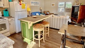 Eine Küche mit Kühlschrank, Herd und hölzernen Barhocker.