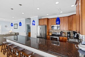 A modern kitchen with a large island, stainless steel appliances, and wooden cabinets.