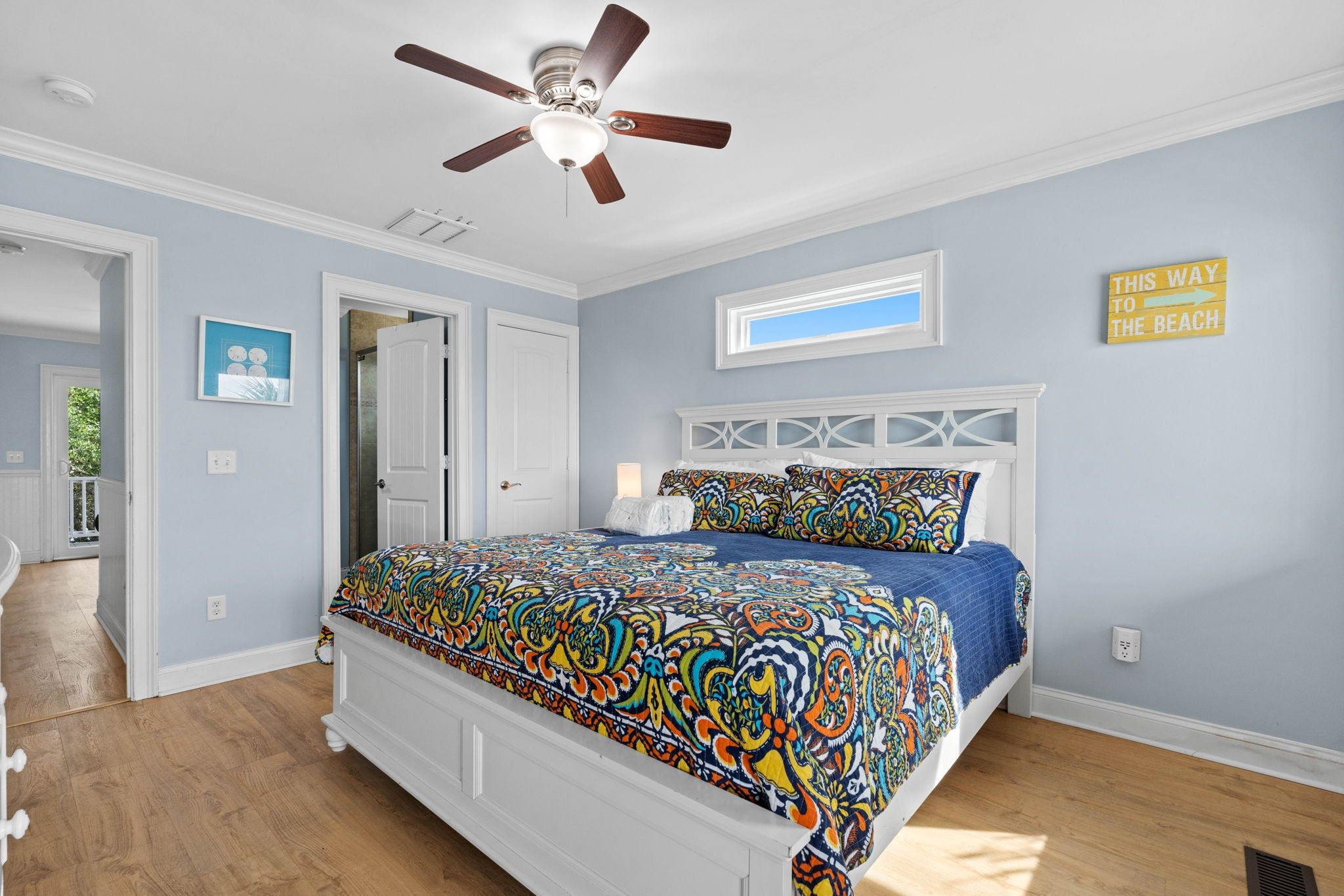 A bedroom with a bed, a ceiling fan, a window, and a door.