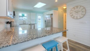 A modern kitchen with granite countertops, white cabinets, and a built-in refrigerator. - Discover ocean views at Salt Shack, Oak Island! Perfect for families and pets, sleeps 8. (Oak Island)