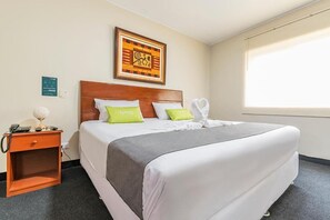 Relax in a serene space with a comfortable bed, nightstand, and artwork.