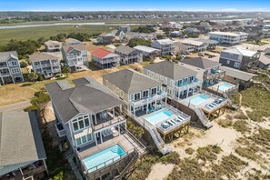 A coastal residential area with multiple houses, some with attached decks and swimming pools.