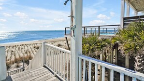 Una terraza de madera que da a una playa con vista despejada al océano.