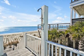 Eine Holzterrasse, die zu einem Strand führt, mit freiem Blick auf das Meer.