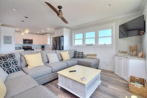 A modern living room with a sectional sofa, a coffee table, and a TV mounted on the wall.