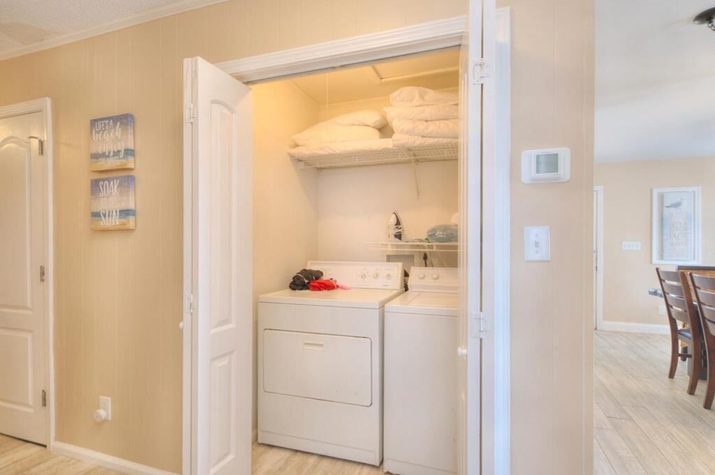 A laundry room with a washer and dryer, a towel rack, and a small shelf with folded towels.