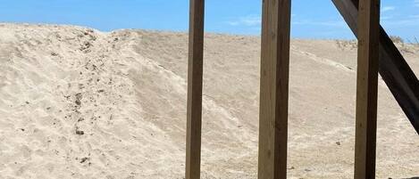 A wooden structure with a staircase leading up to a platform, surrounded by sand dunes.
