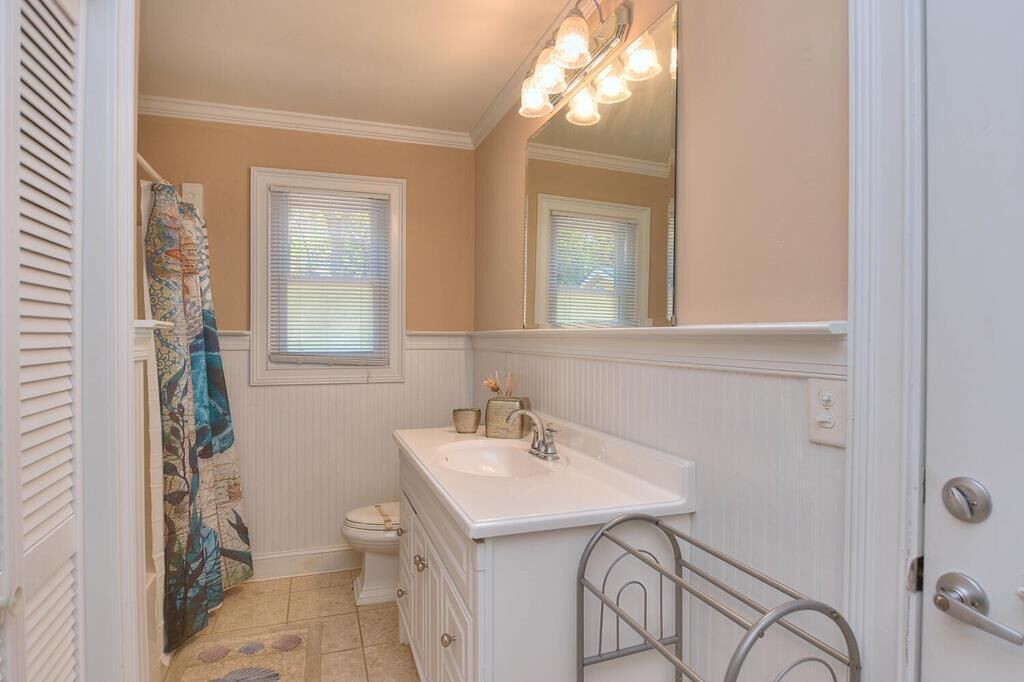 A bathroom with a white sink, a mirror, and a toilet.