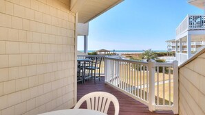 Un balcon avec vue sur la plage, une table et des chaises.