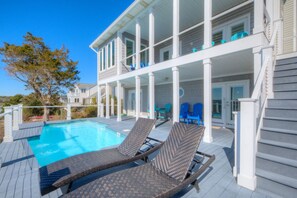 A poolside area with lounge chairs, a pool, and a covered deck.