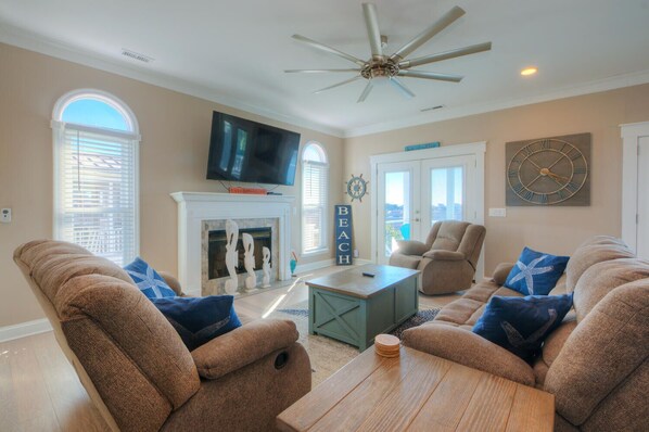 A living room with a fireplace, a television, and a ceiling fan.