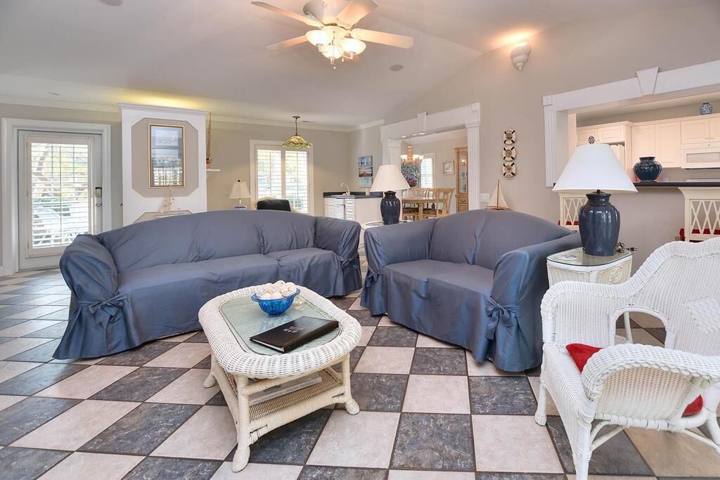 A living room with two grey sofas, a wicker coffee table, and a white wicker chair.