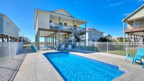 A residential property with a swimming pool, a covered patio, and a two-story house with a balcony. - The Jolly Rogers: Oceanview house in Oak Island with private pool and spacious layout. (Oak Island)