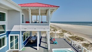 Une propriété située en bord de mer, dotée d’un patio couvert, d’un espace salon extérieur et d’une piscine.