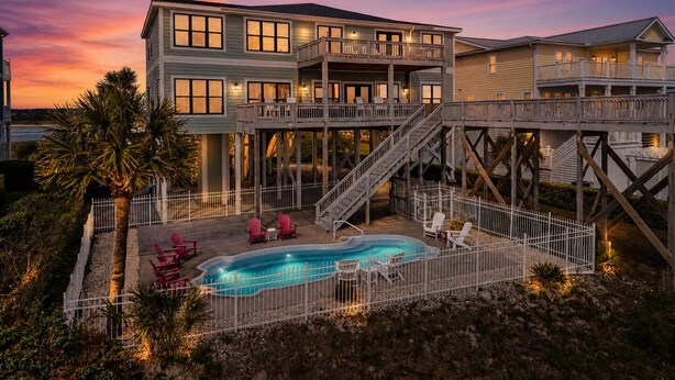 Una casa de dos pisos con piscina, terraza y una escalera que conduce a un balcón.