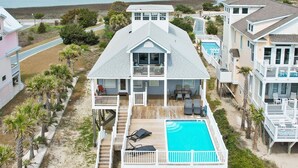 Ein zweistöckiges Haus mit einer großen Terrasse und einem Swimmingpool.