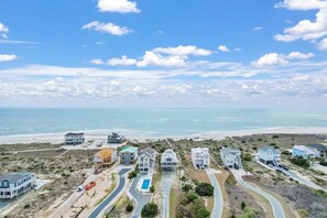 A coastal residential area with houses, a swimming pool, and a beach.