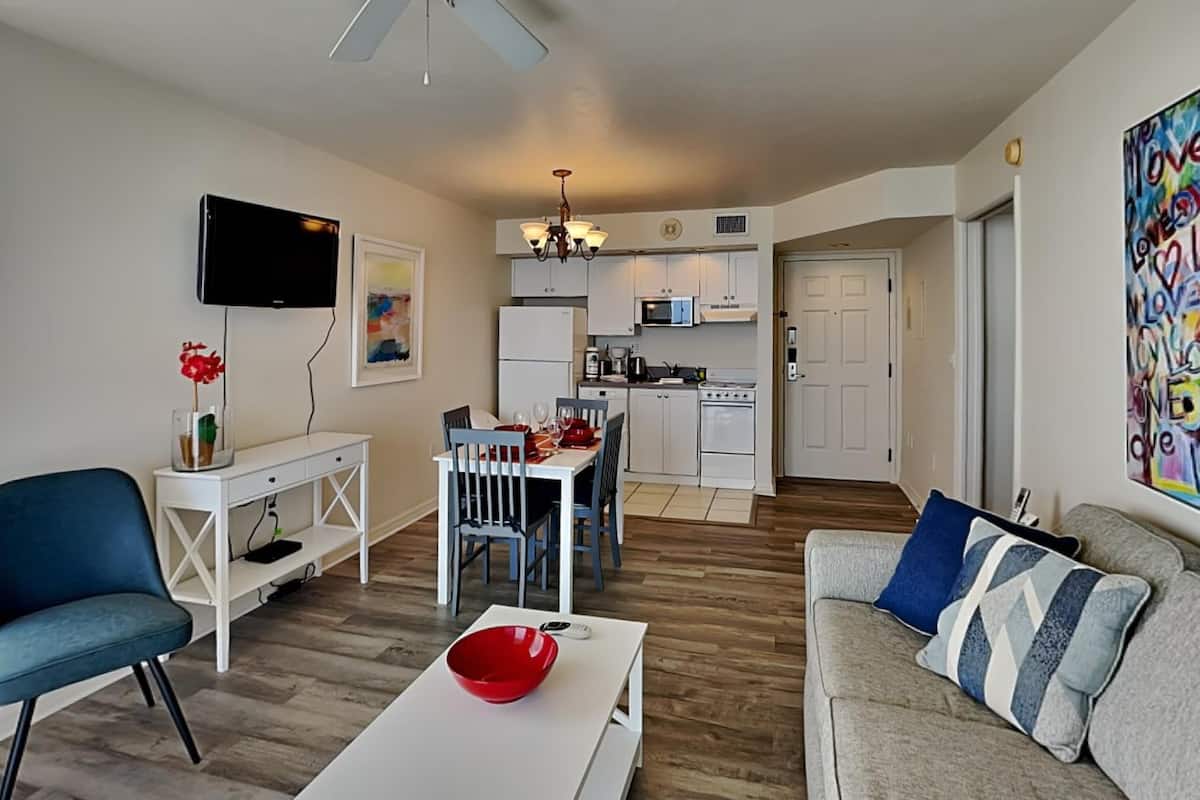 A modern apartment with a dining area, kitchen, living room, and a ceiling fan.