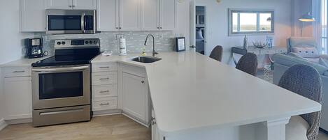 A modern kitchen with white cabinetry, stainless steel appliances, and a large island.