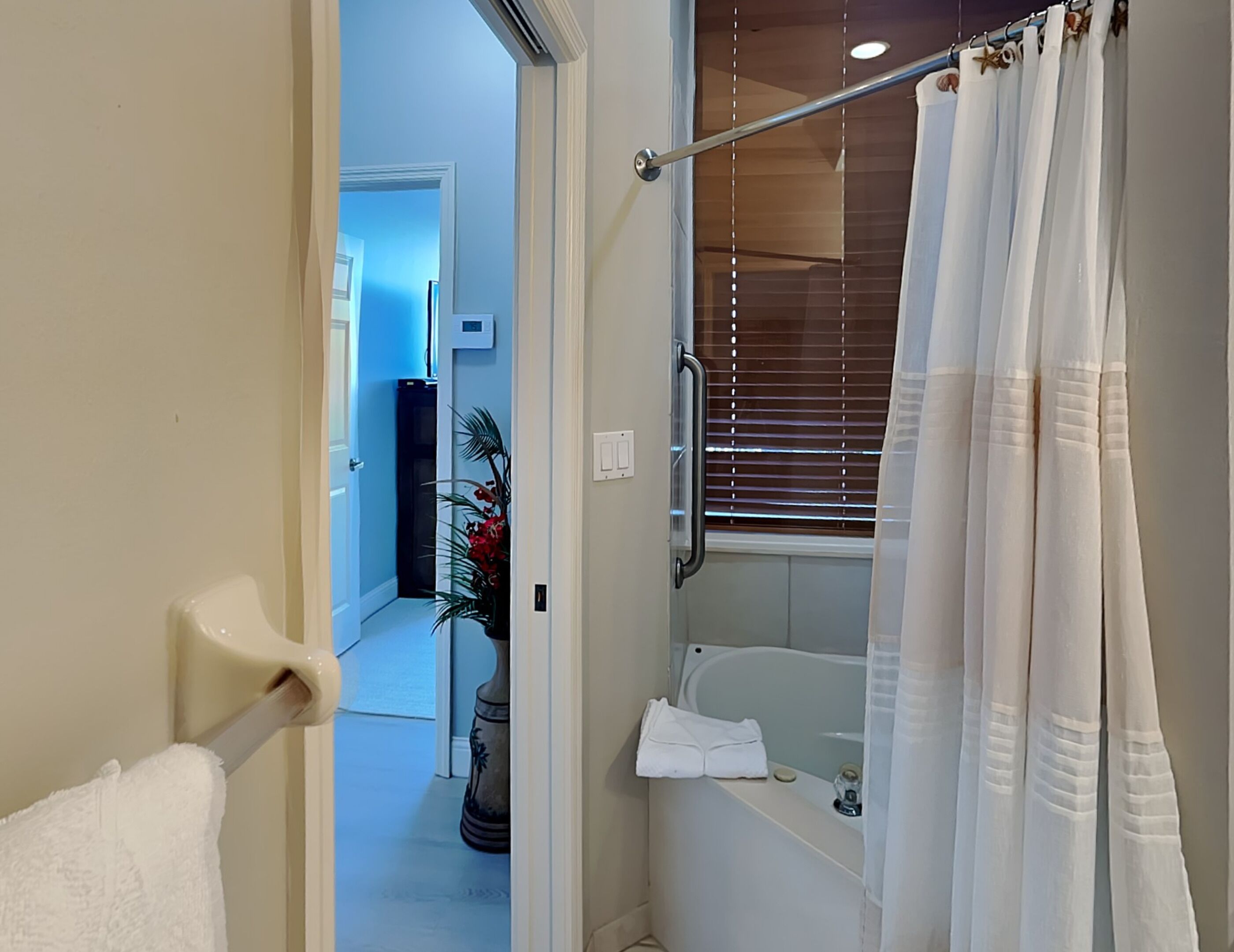 A bathroom with a bathtub, a shower curtain, and a towel rack.