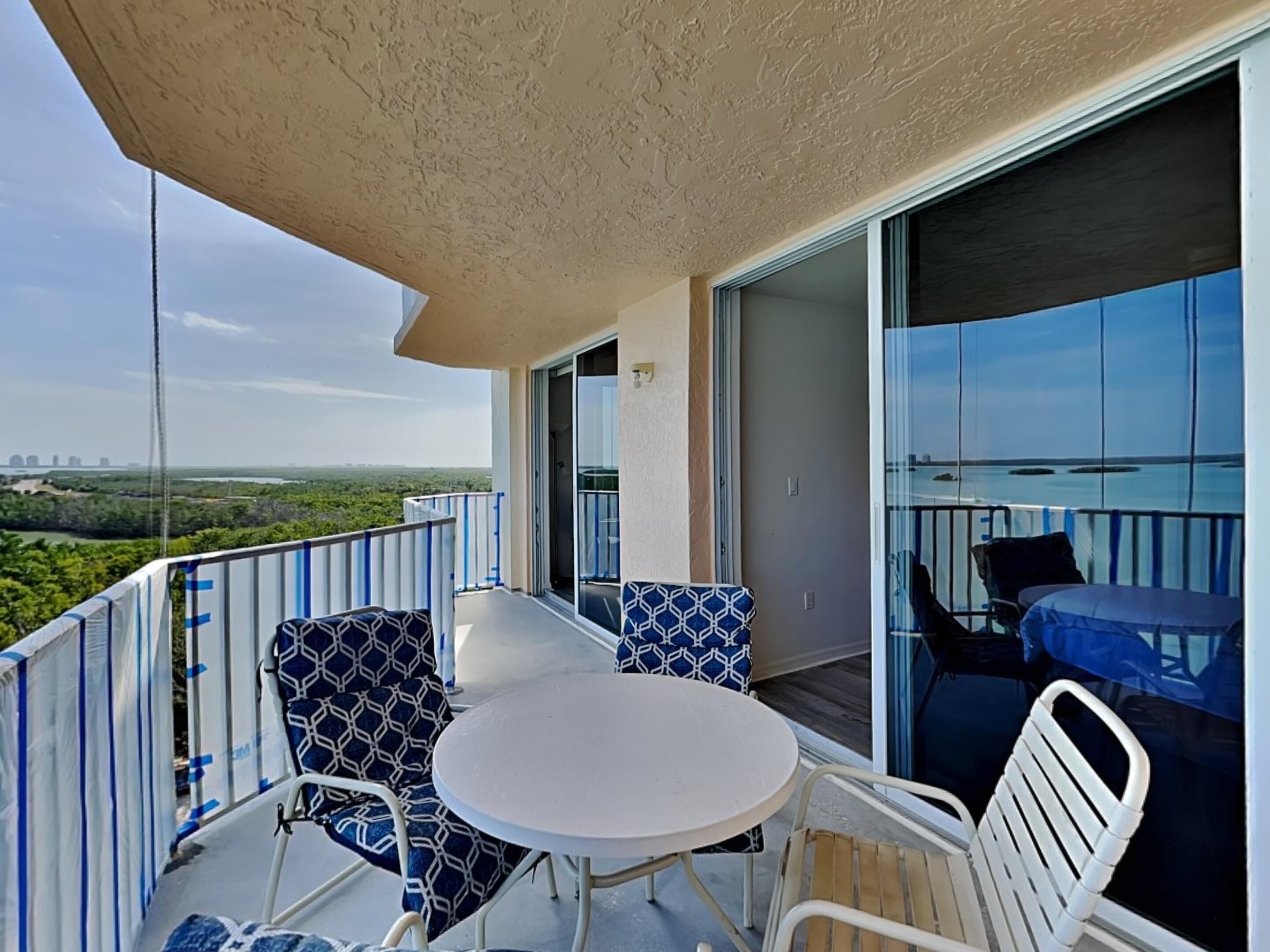 Een balkon met een tafel en stoelen, een uitzicht over de stad en een schuifdeur.
