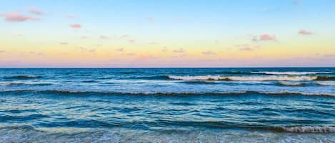 A beach with waves and a clear sky.