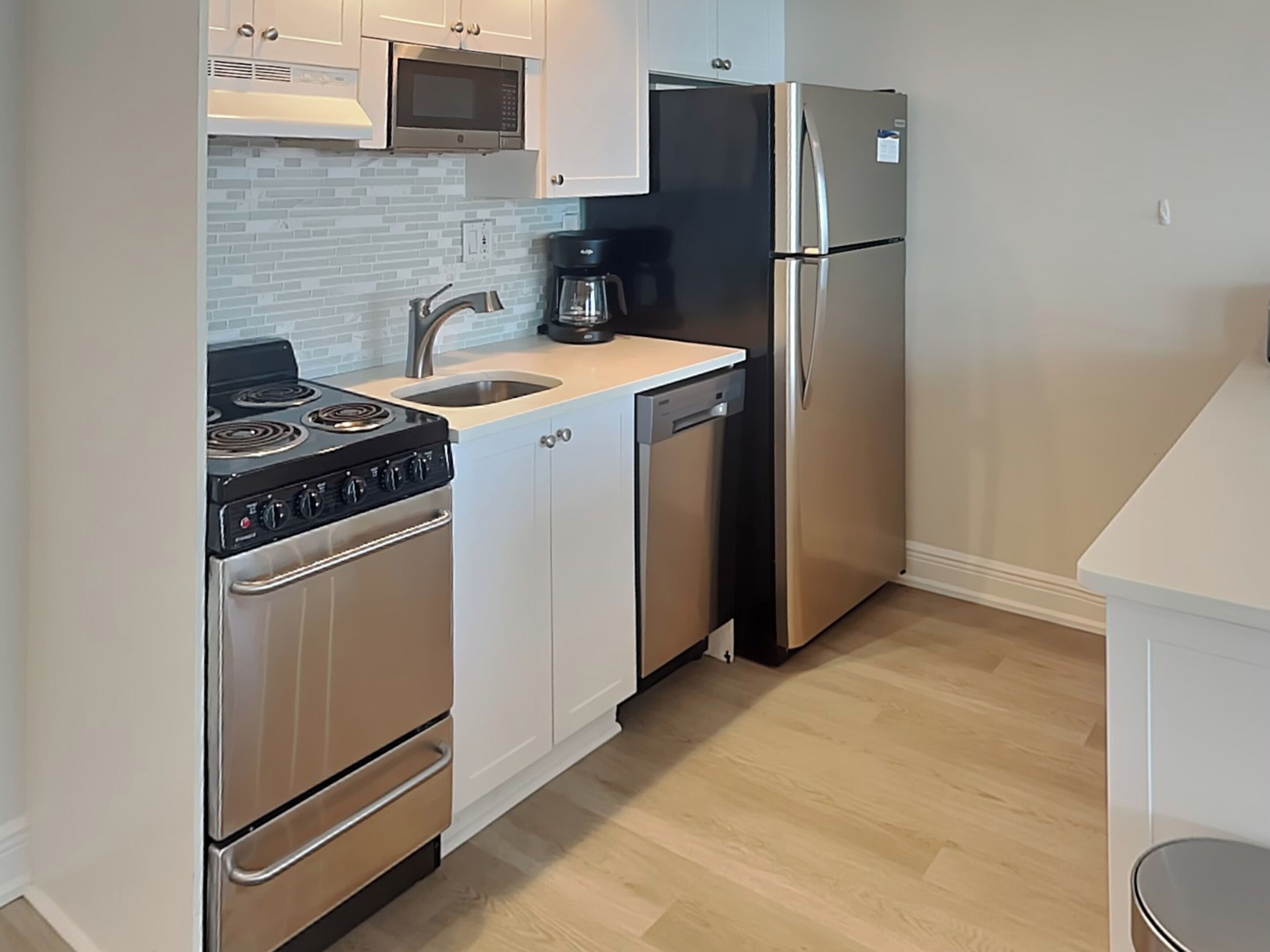 A compact kitchen with a stove, microwave, sink, and refrigerator.