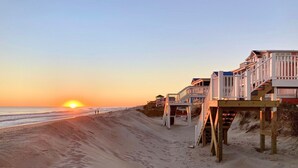 A beach with wooden walkways leading to beach houses. - Discover Zion in Oak Island: an oceanfront dream with 5 bedrooms for 12 guests! (Oak Island)