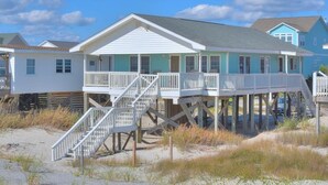 A beachfront house with a balcony and a wooden deck. - Oceanfront haven in Oak Island—spacious 3BR, 2BA home for up to 8 guests! (Oak Island)