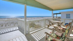 A wooden deck with a white railing overlooking a beach. - Oceanfront haven in Oak Island—spacious 3BR, 2BA home for up to 8 guests! (Oak Island)