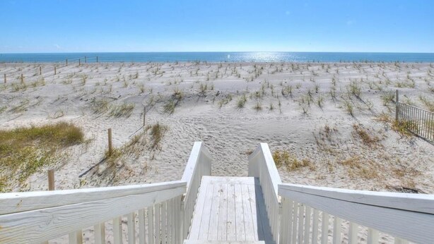 A wooden boardwalk leading to a sandy beach with sparse vegetation. - Oceanfront haven in Oak Island—spacious 3BR, 2BA home for up to 8 guests! (Oak Island)