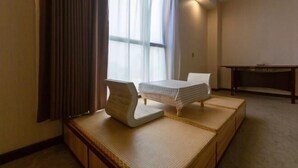 A hotel room with a bed, a small table, and a window with curtains. - Nishi Kingmau Hotel (Changzhou)