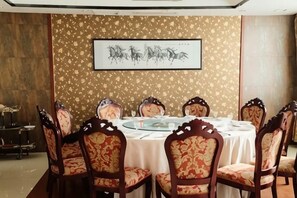 Una zona de menjador amb una taula rodona, cadires i una obra d'art emmarcada a la paret.