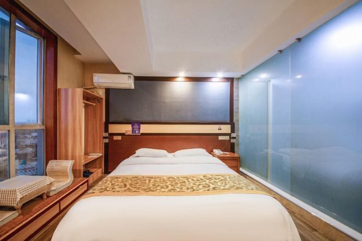 Ein Hotelzimmer mit Bett, Nachttisch, Sessel, Kleiderschrank und großem Fenster.