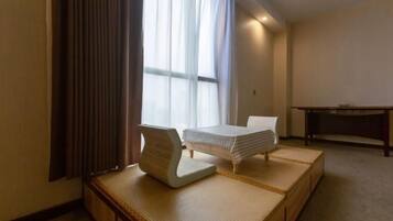 A hotel room with a bed, a desk, and a futon seating area.