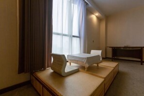 Ein Hotelzimmer mit Bett, Schreibtisch und einer Sitzecke mit Schlafsofa.