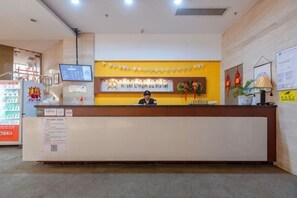 Un taulell de recepció d'hotel amb una pantalla digital, una placa senyalitzadora i un mostrador d'atenció al client.