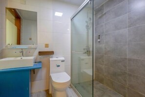 A bathroom with a glass-enclosed shower, a white toilet, and a blue sink.