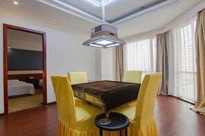 Ein Hotelzimmer mit einem Bett, einem Tisch mit gelben Stühlen, einer Deckenleuchte und einem Fenster mit Vorhängen.