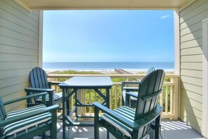 A balcony with a view of the ocean, featuring green Adirondack chairs and a small table. - Enjoy stunning ocean views at OIBV 107, a spacious 3-bedroom condo in Caswell Beach. (Caswell Beach)